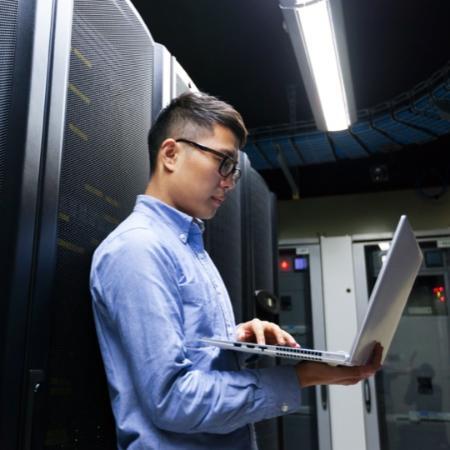 Man looks at a computer within a server room.